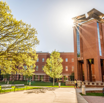 Campus library, on a sunny fall day with a sun flare shining at the top of the building
