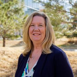 Debbie Lammers Headshot with evergreens in the background